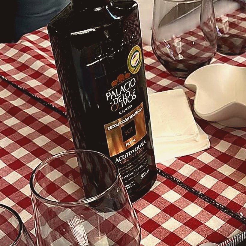 A bottle of award-winning extra virgin olive oil on a gingham tablecloth