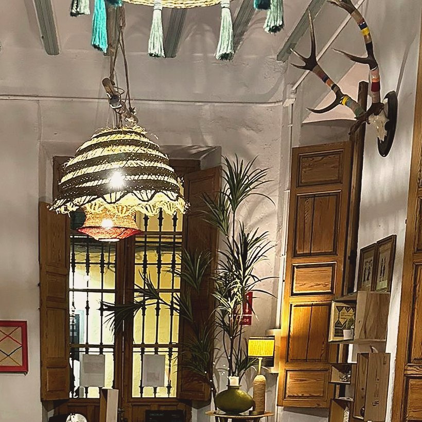 An Andalusian room with exposed beams, a wicker pendant lamp and a shuttered window